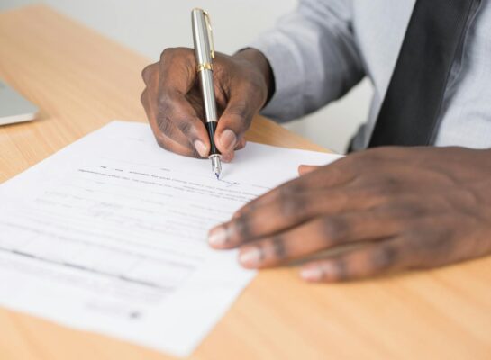 Close-up of a businessman signing a contract at an office desk.